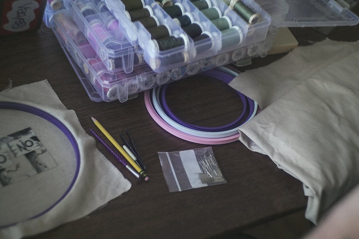 A desk is scattered with embroidery tools.